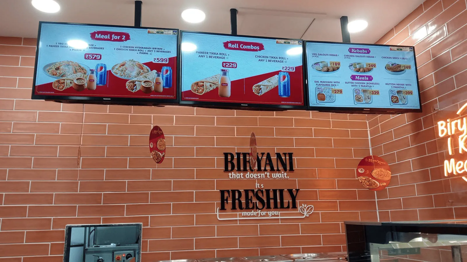 Menu screens above the counter at a Biryani By Kilo outlet